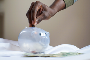 Clear piggy bank with hand putting coins in